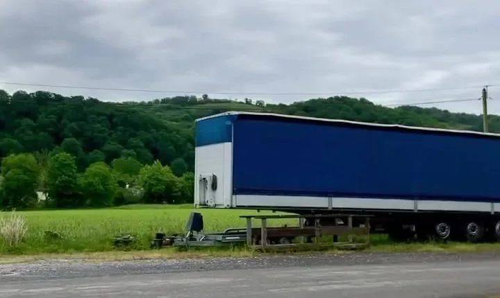 Semi-remorque bâchée bleue stationnée au bord d'une route de campagne